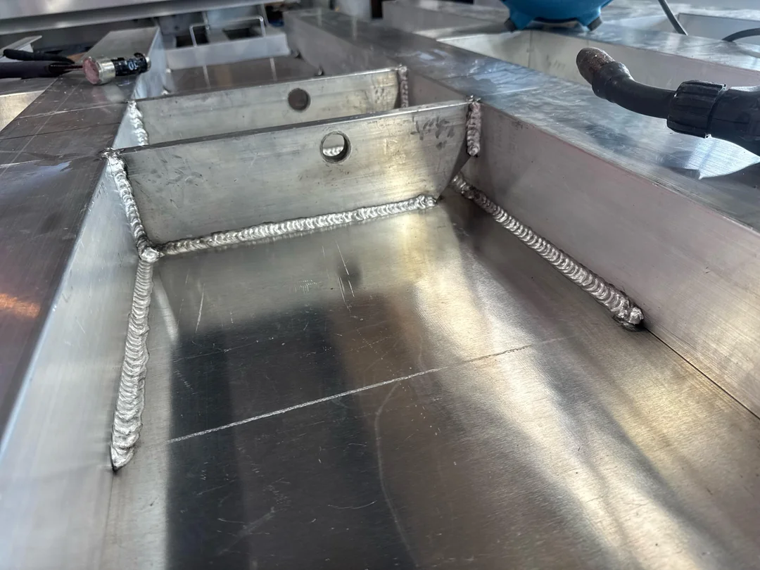 Aluminium fabrication with long fillet welds inside a tray